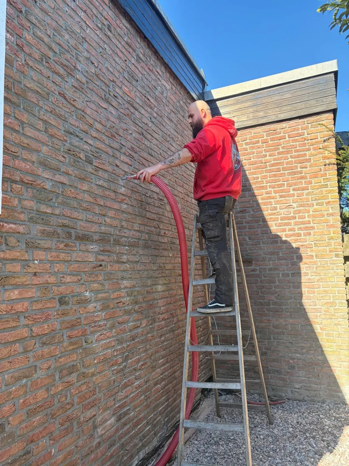 Josh beim Einblasen einer Hohlschicht an einer Klinkerfassade